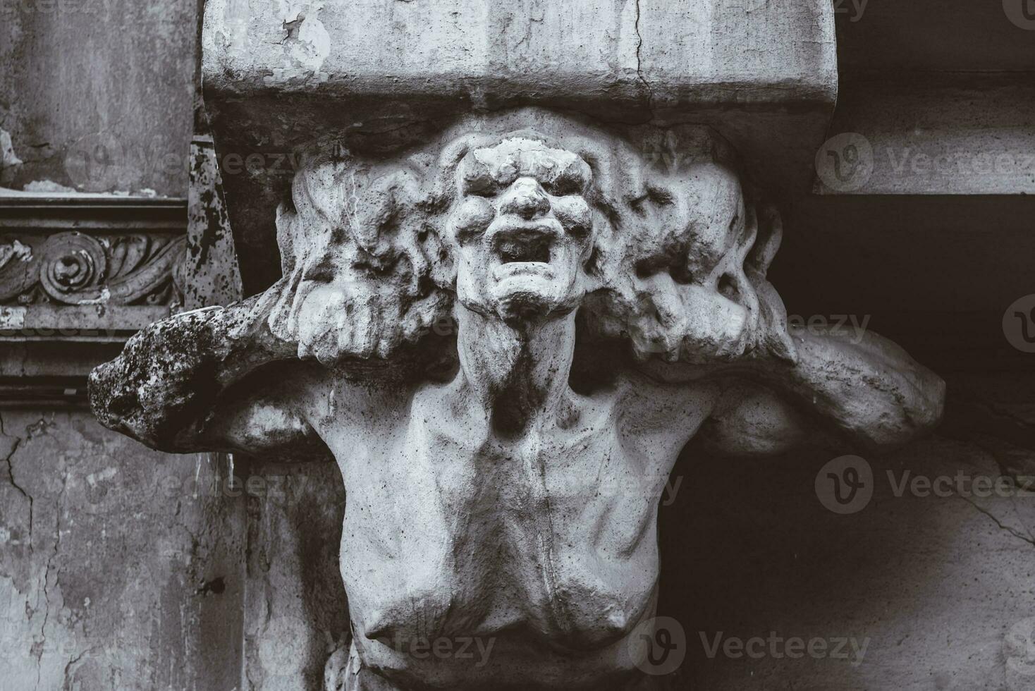 bust of concrete of a terrible woman on the facade of an old house photo