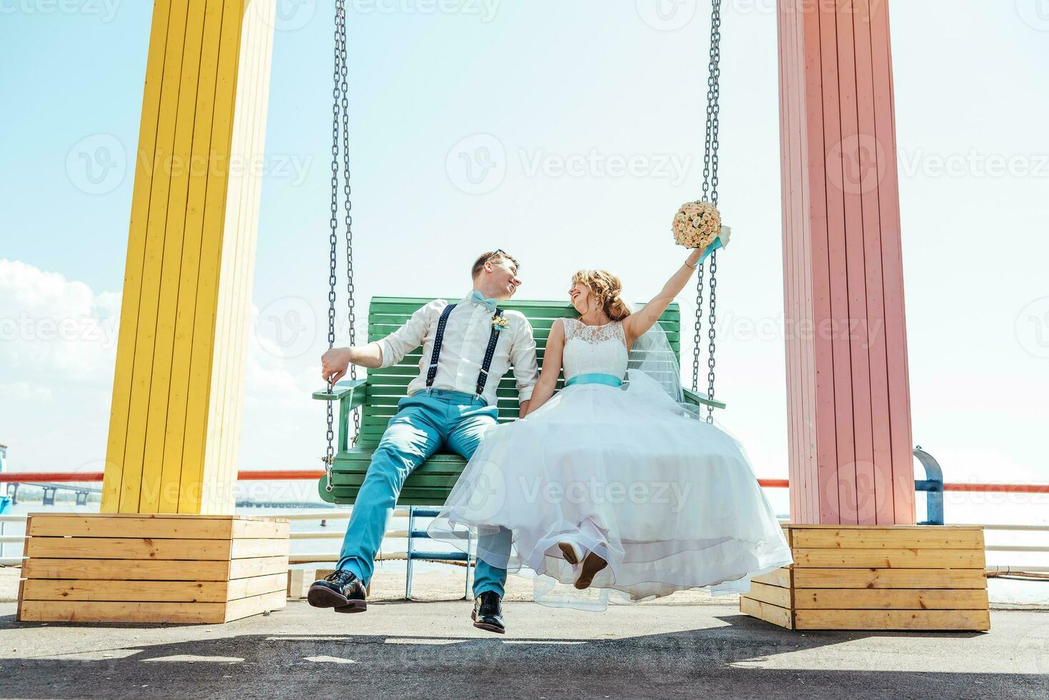 the bride and groom ride on a swing photo