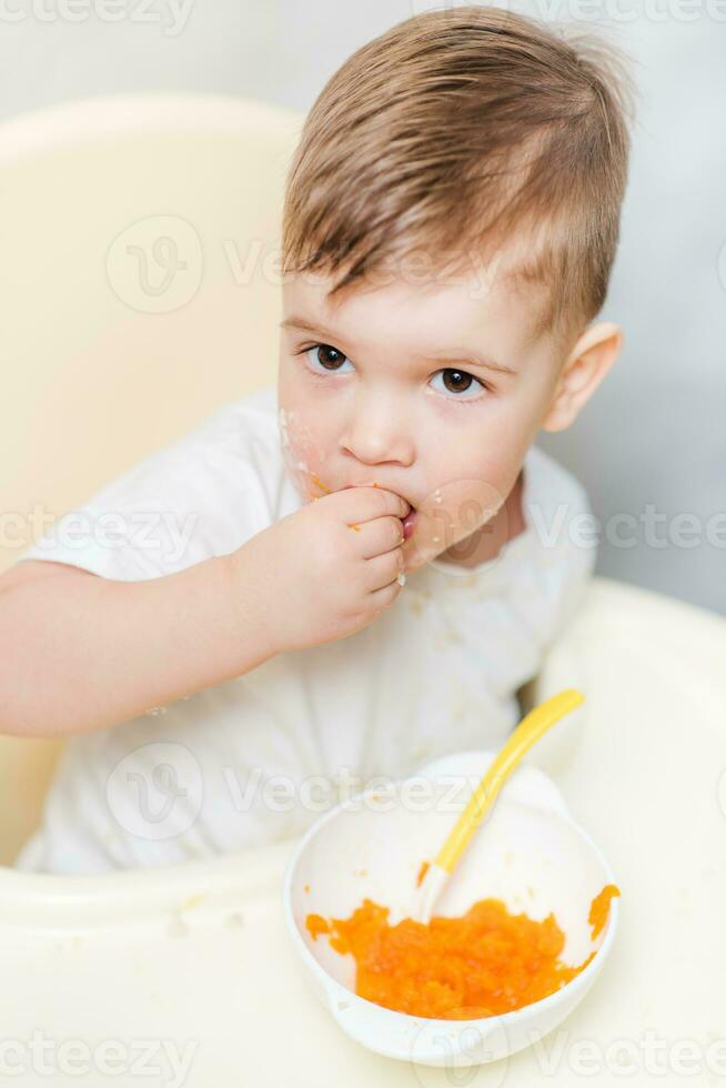 cute toddler eating a pumpkin with a small spoon himself photo