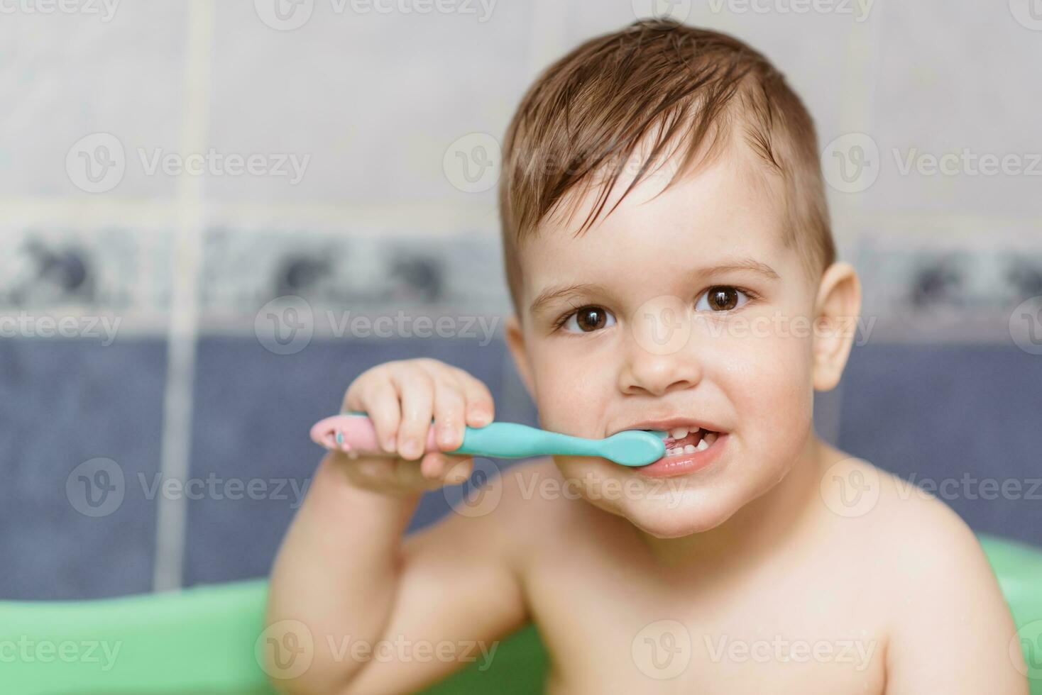 encantador bebé cepillado su dientes con un cepillo de dientes en el baño foto