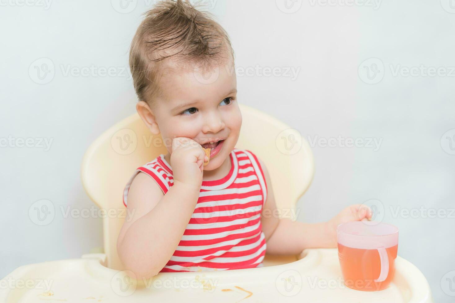 pequeño bebé come galletas y bebidas compota en el cocina foto