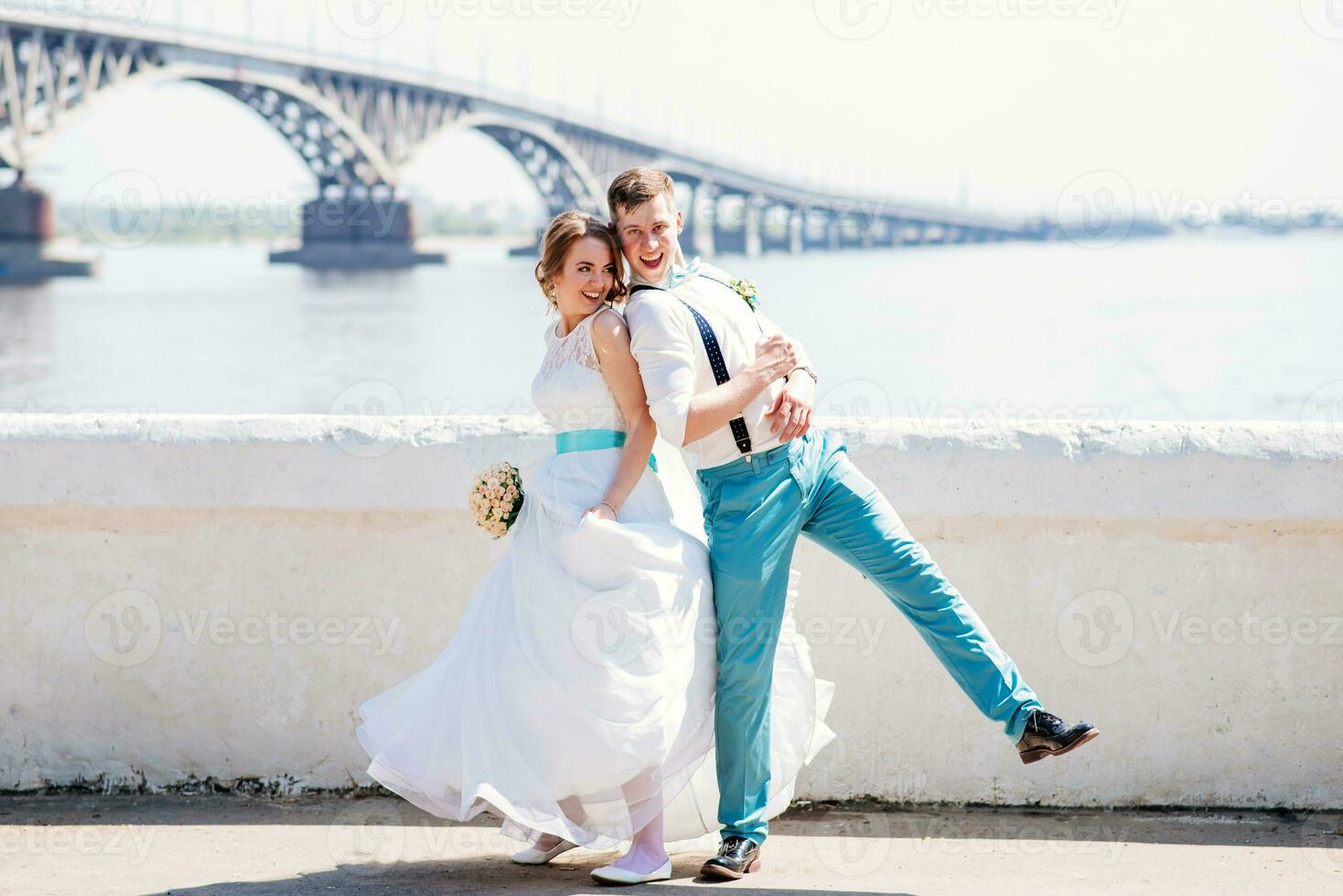 the bride and groom are photographed on the background of the bridge photo