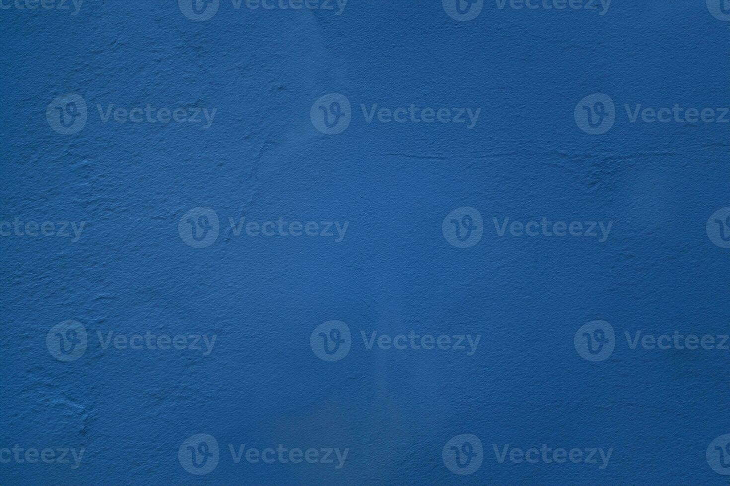 A close up photo of an exterior textured wall painted blue, surface with stucco daub, great for background