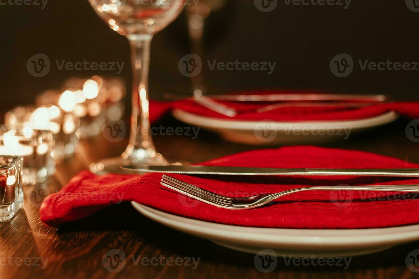 Christmas table setting. Plate and cutlery on napkin. Preparing for festive dinner. Candles burning on table on Christmas Eve. photo