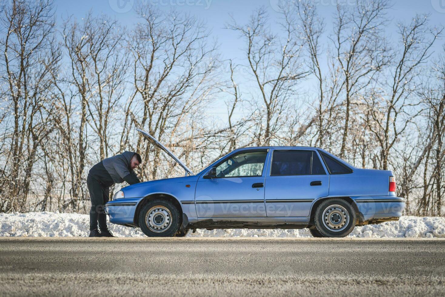 man repairing a car standing at the hood photo