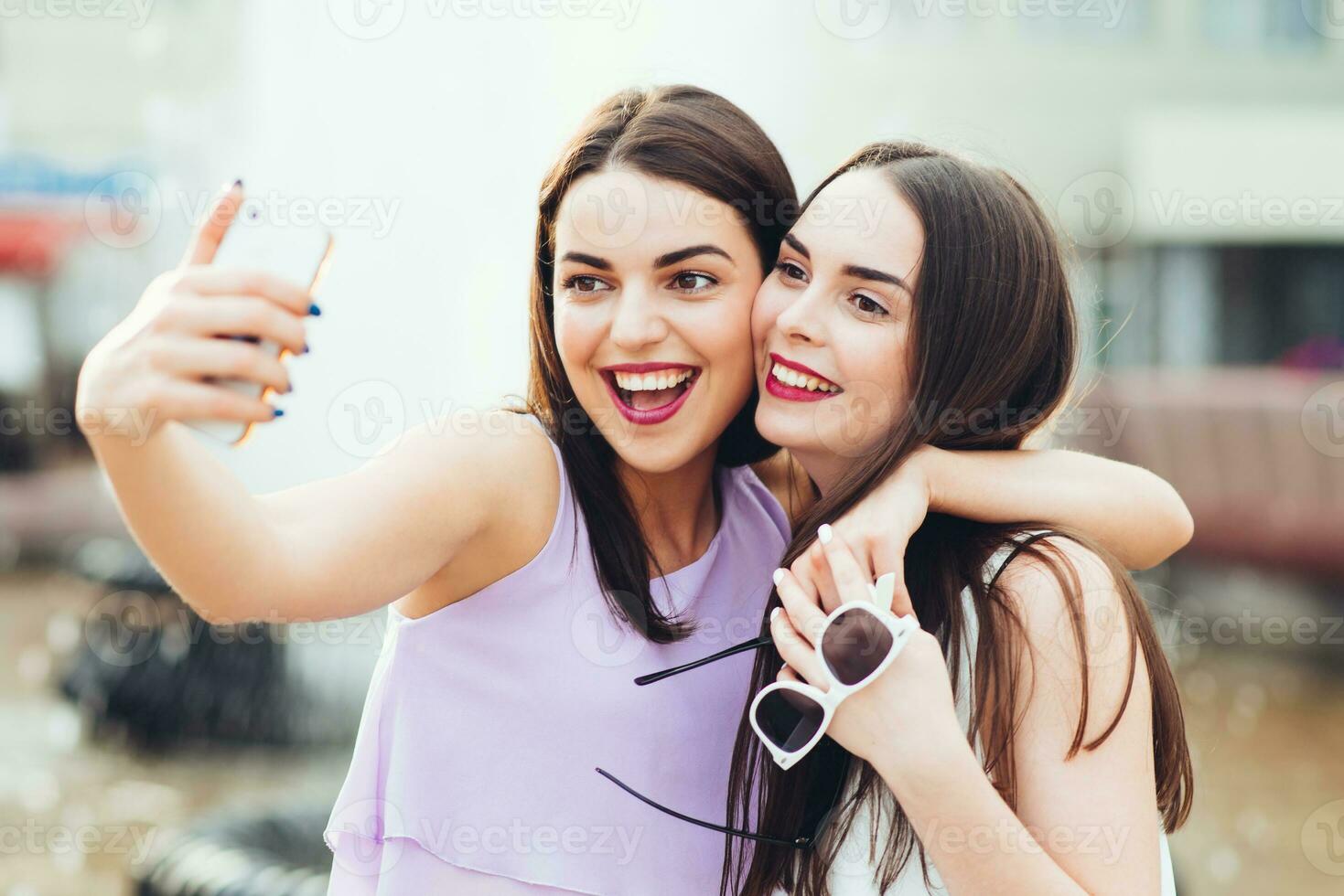 Two beautiful sisters do selfie on the street photo