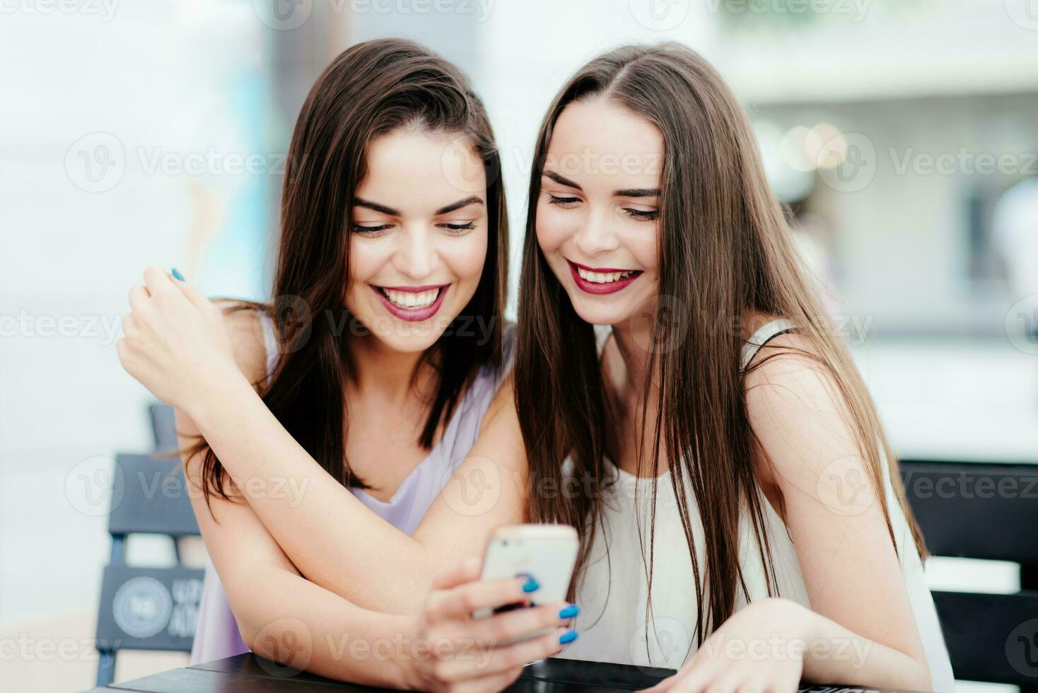 muchachas tener divertido con un teléfono en café foto