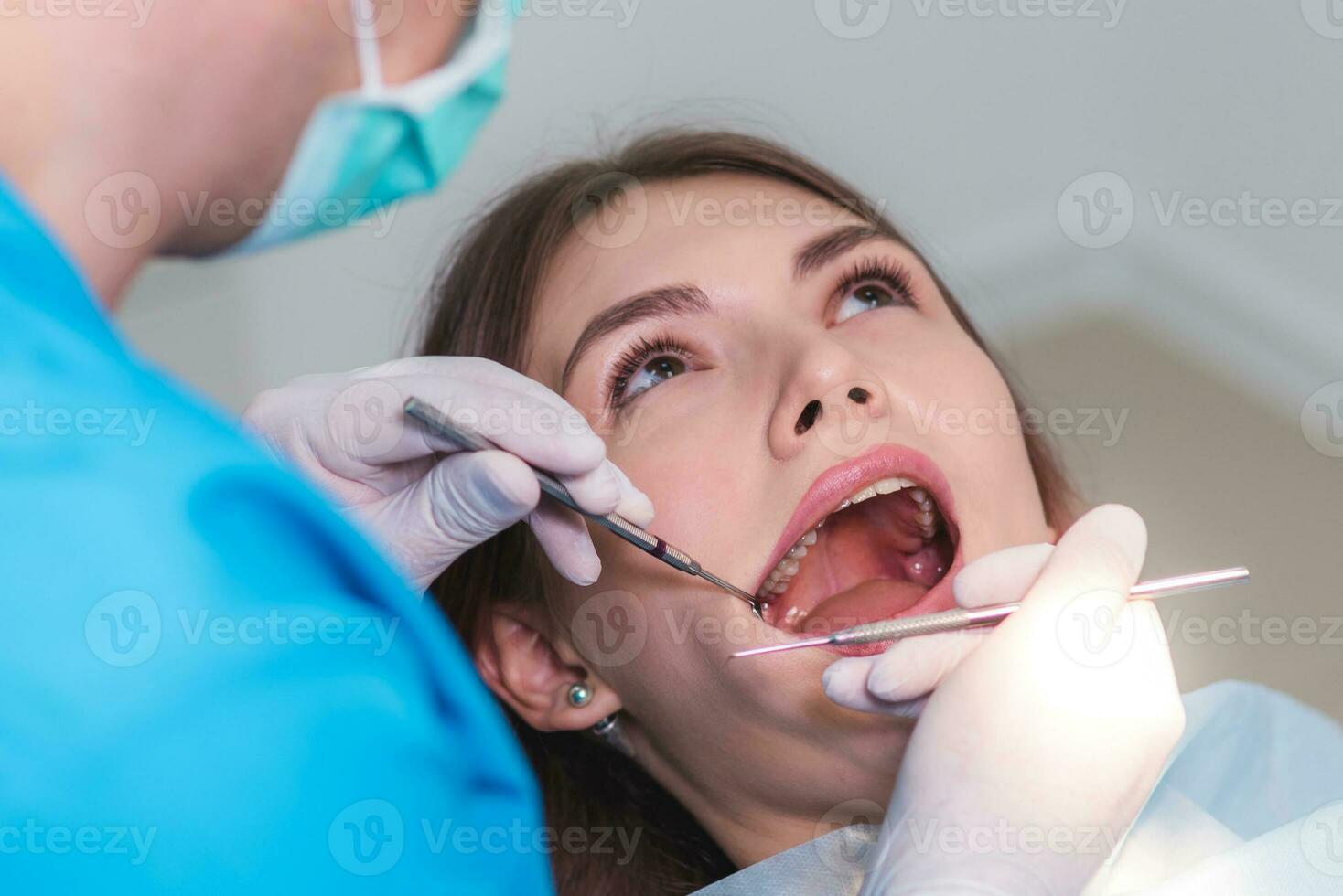 doctor orthodontist examines the oral cavity of a beautiful patient photo