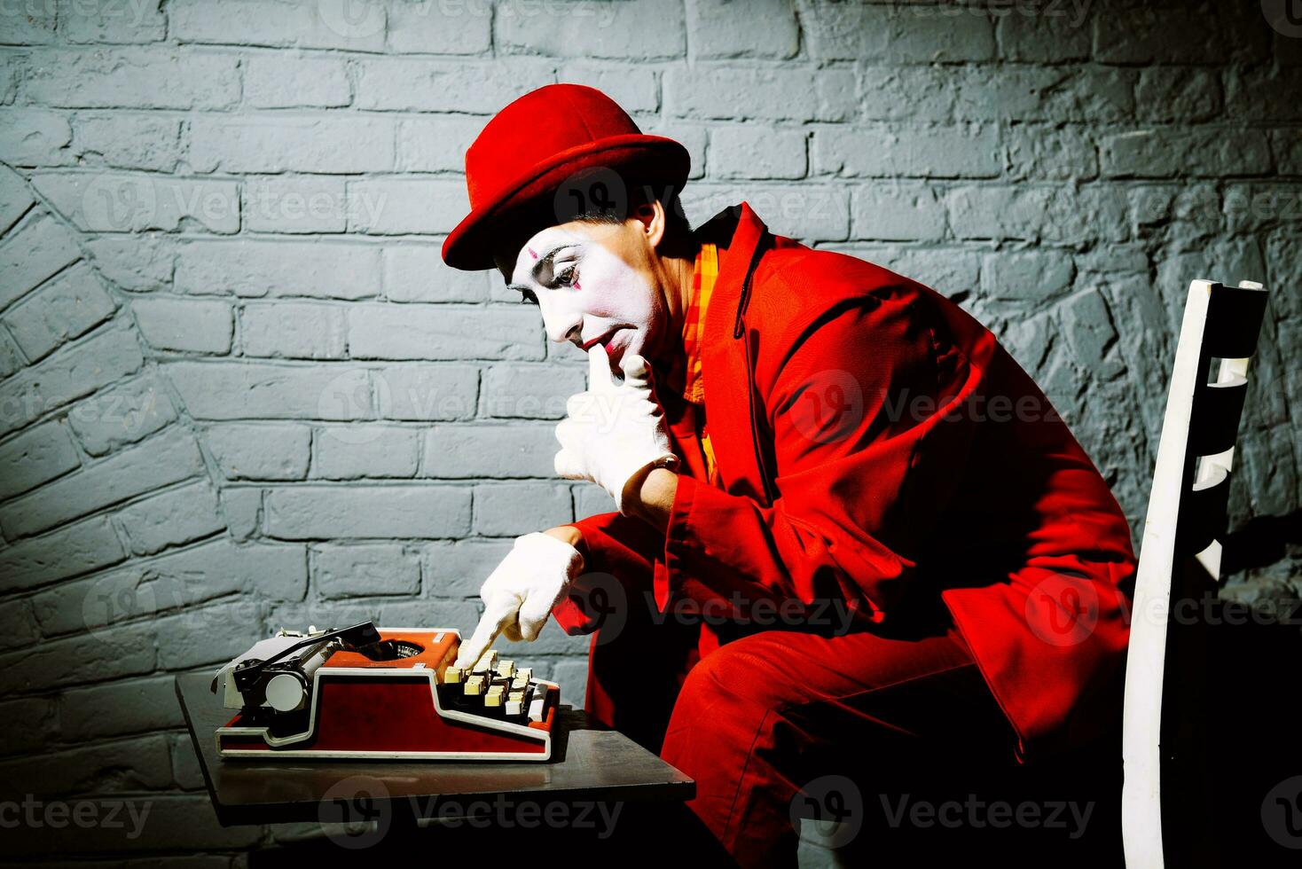 Mime in a red suit prints on a typewriter photo