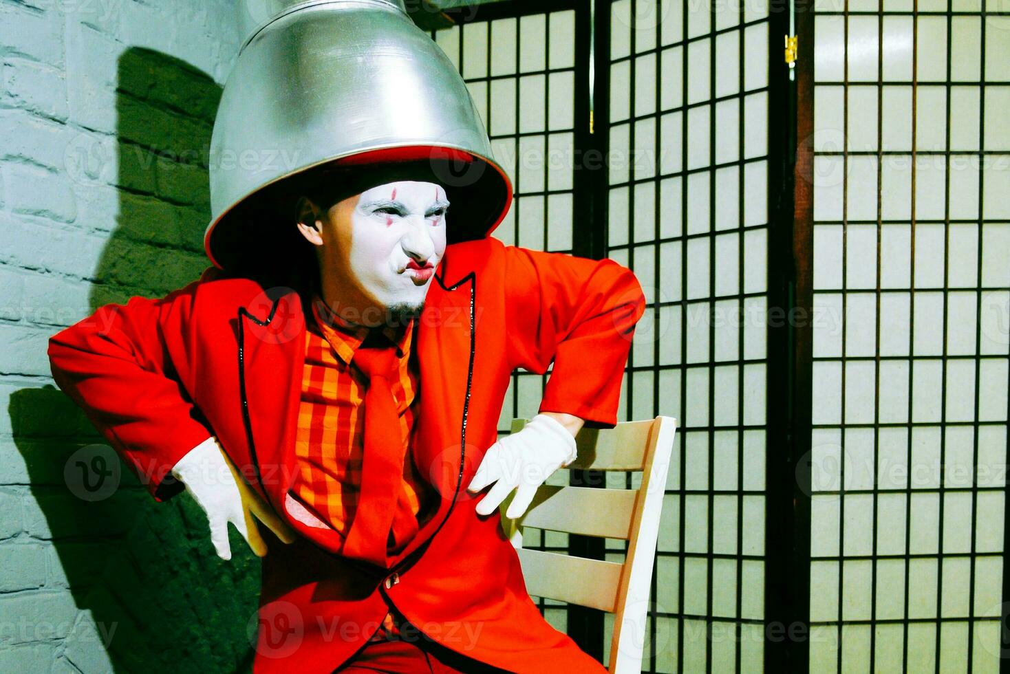 Mime put a metal lampshade on his head, makes faces and poses photo