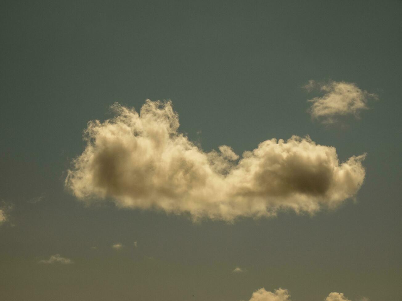 Single fluffy cloud over sunset sky background. Fluffy cumulus cloud shape photo