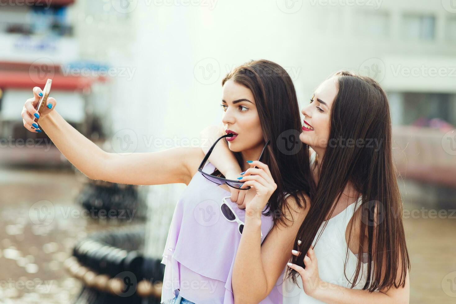 Two beautiful sisters do selfie on the street photo