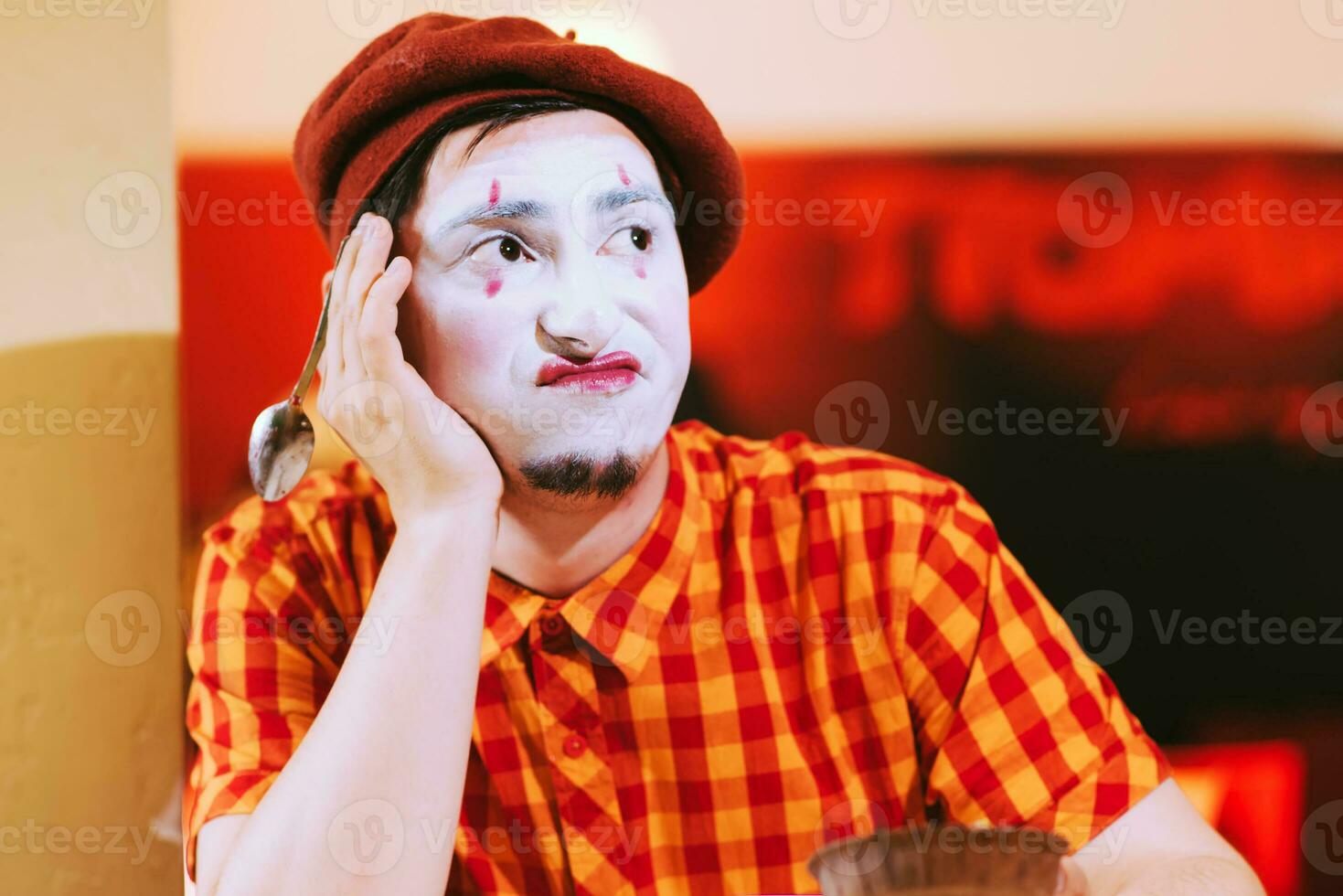 el payaso es comiendo un pastel en un café y su cara es croando. foto