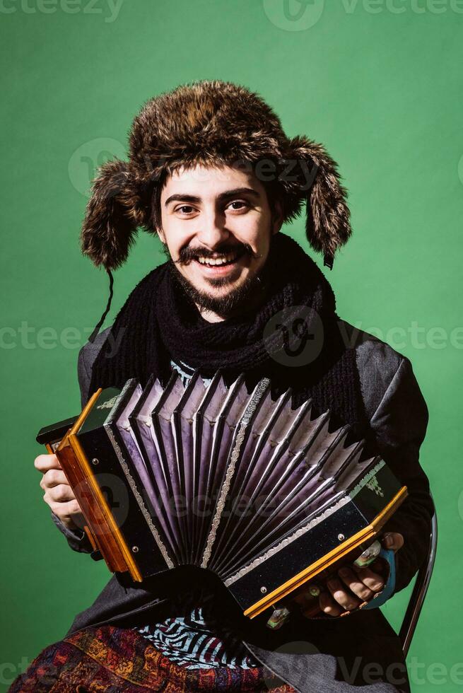 un muy positivo hombre con un acordeón posando en el estudio foto