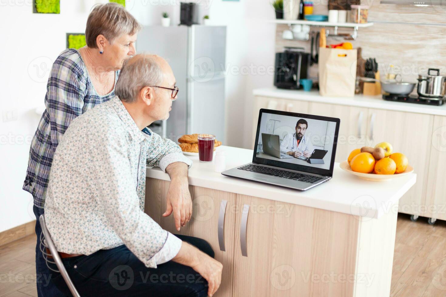 Senior couple having a video conference with doctor talking ill treatment using laptop webcam. Online health consultation for elderly people drugs ilness advice on symptoms, physician telemedicine webcam. Medical care internet chat photo