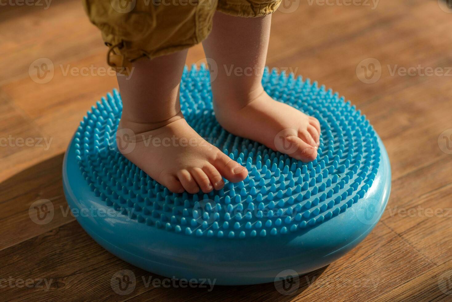 little kid massages his feet while standing on the rug photo