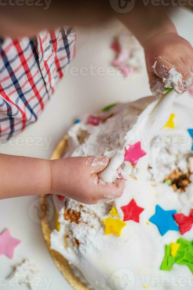 Little baby touches his birthday cake which lies on the table photo