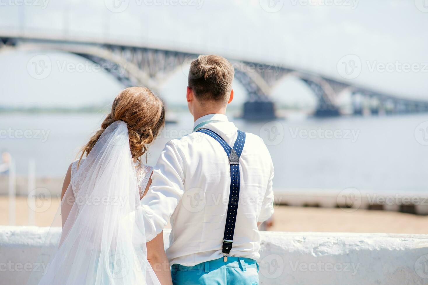 the bride and groom are photographed on the background of the bridge photo