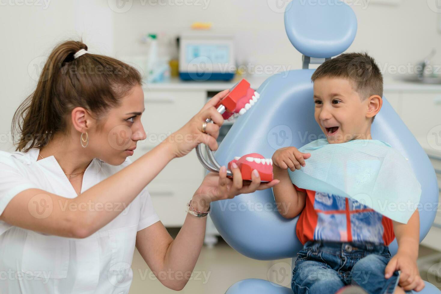 the orthodontist entertains the little patient so that he is not afraid to treat his teeth photo