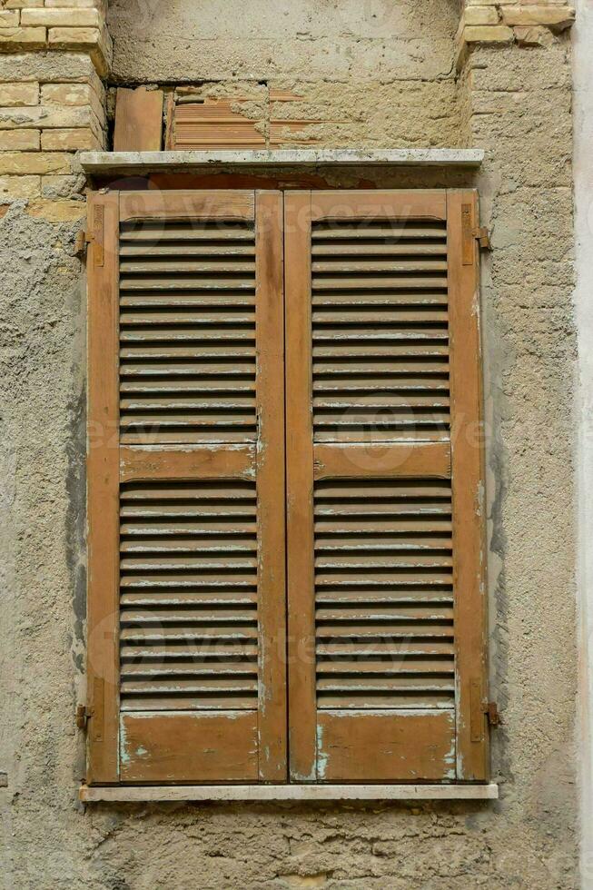 a window with wooden shutters on a brick wall photo