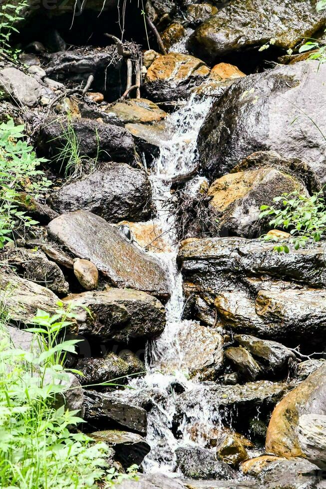 a small waterfall running through a rocky area photo