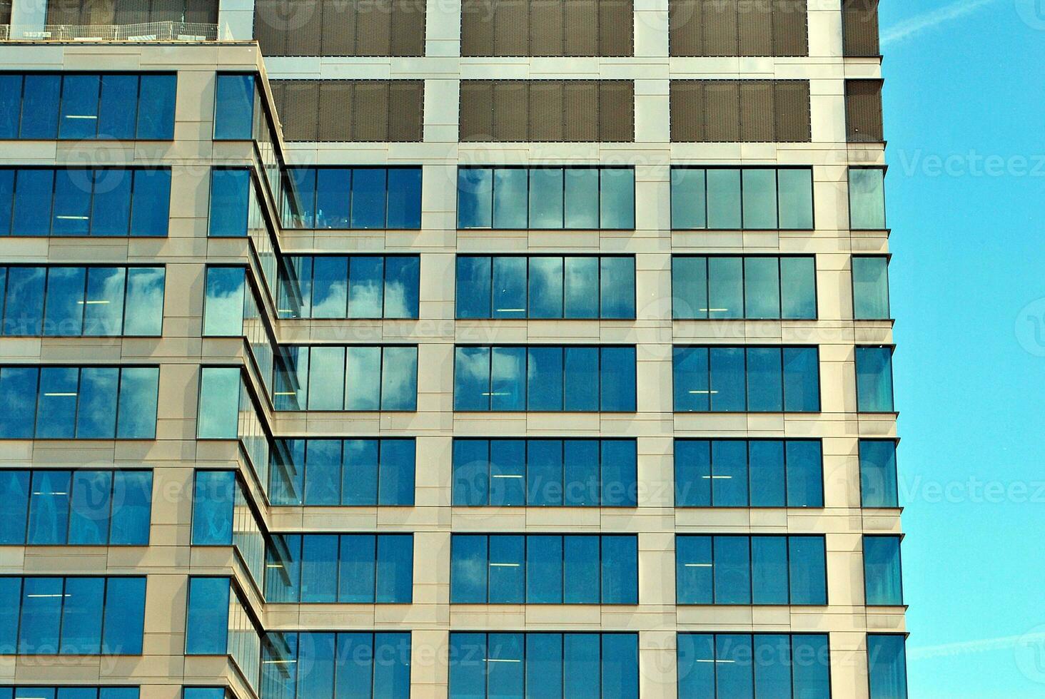 Structural glass wall reflecting blue sky. Abstract modern architecture fragment photo