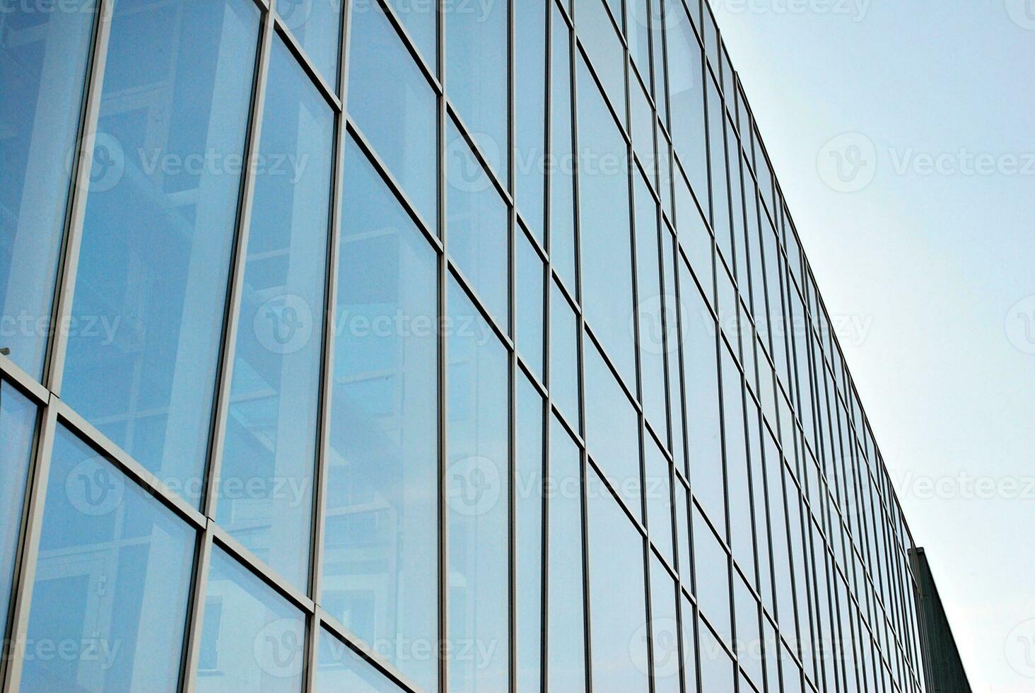 Structural glass wall reflecting blue sky. Abstract modern architecture fragment. photo