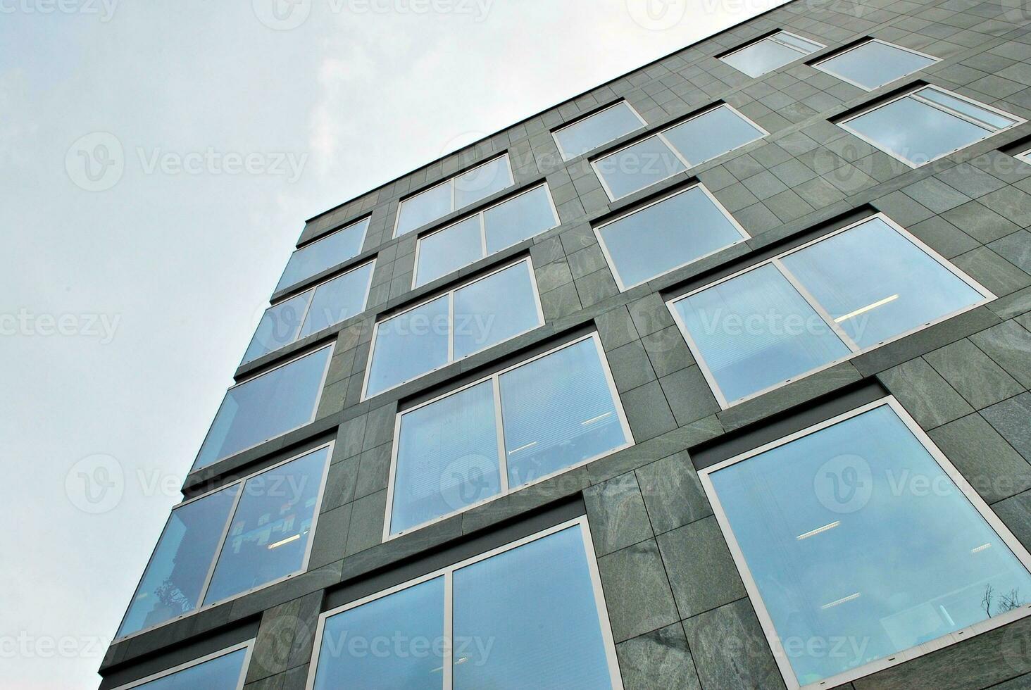 Structural glass wall reflecting blue sky. Abstract modern architecture fragment photo