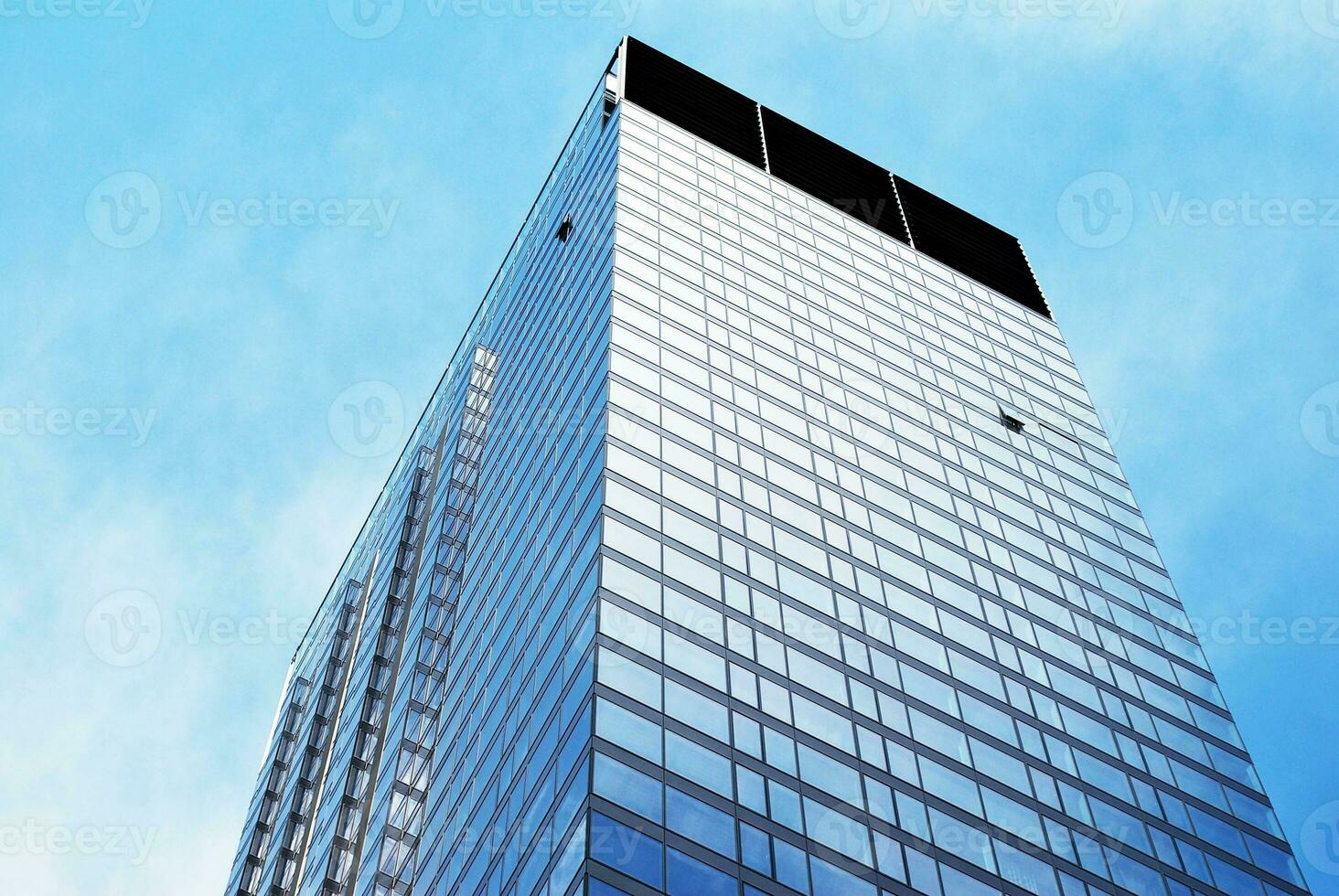 Structural glass wall reflecting blue sky. Abstract modern architecture fragment photo