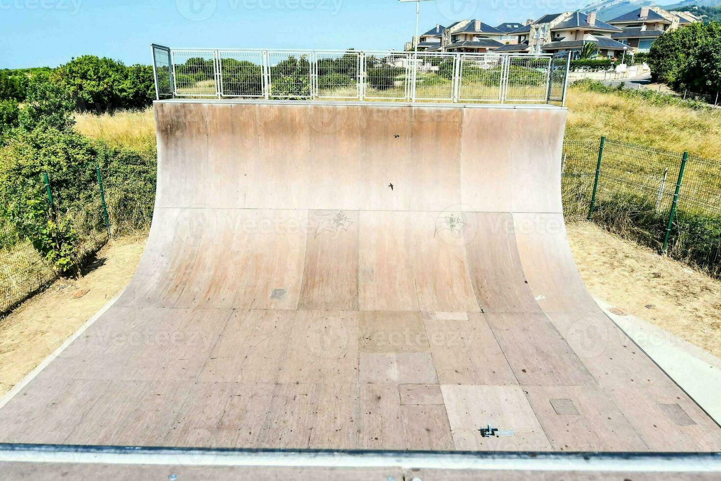a skateboard ramp in a park with a fence photo