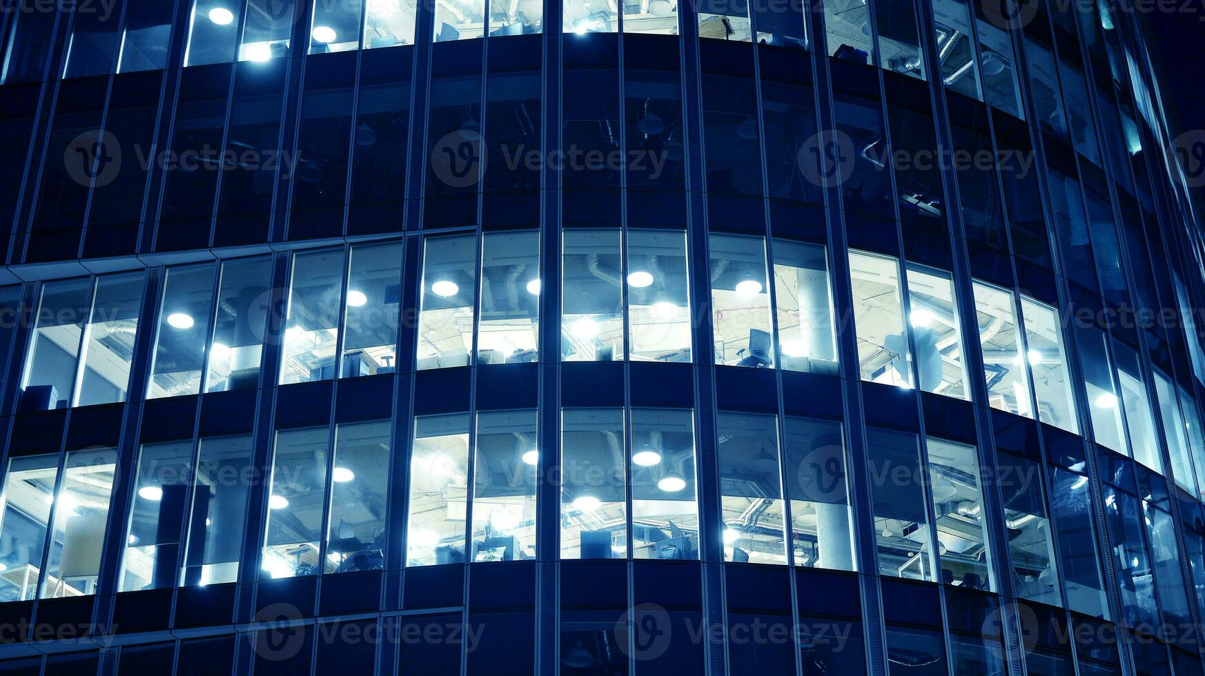 Pattern of office buildings windows illuminated at night. Glass architecture ,corporate building at night - business concept. Blue graphic filter. photo