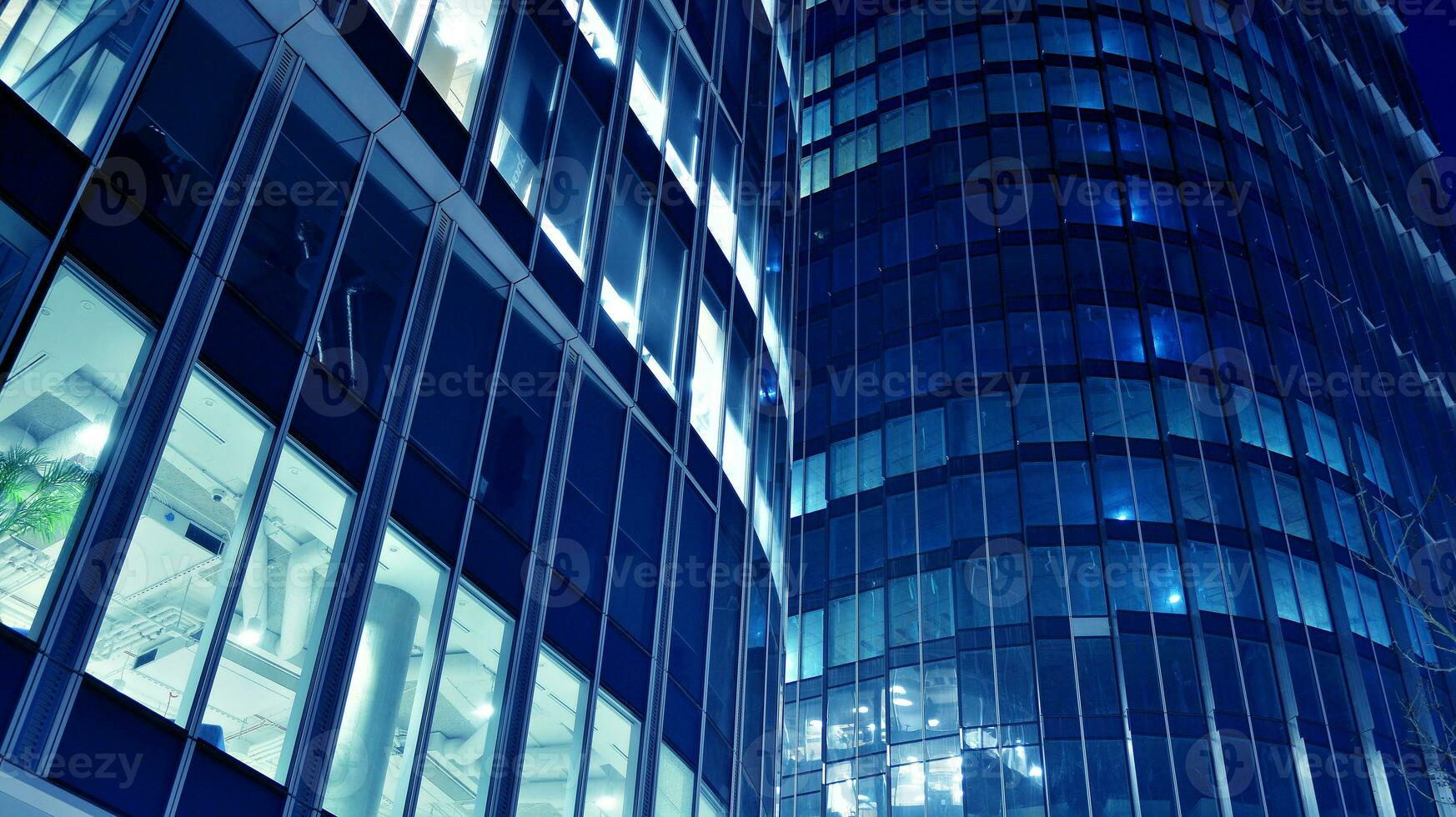 Pattern of office buildings windows illuminated at night. Glass architecture ,corporate building at night - business concept. Blue graphic filter. photo