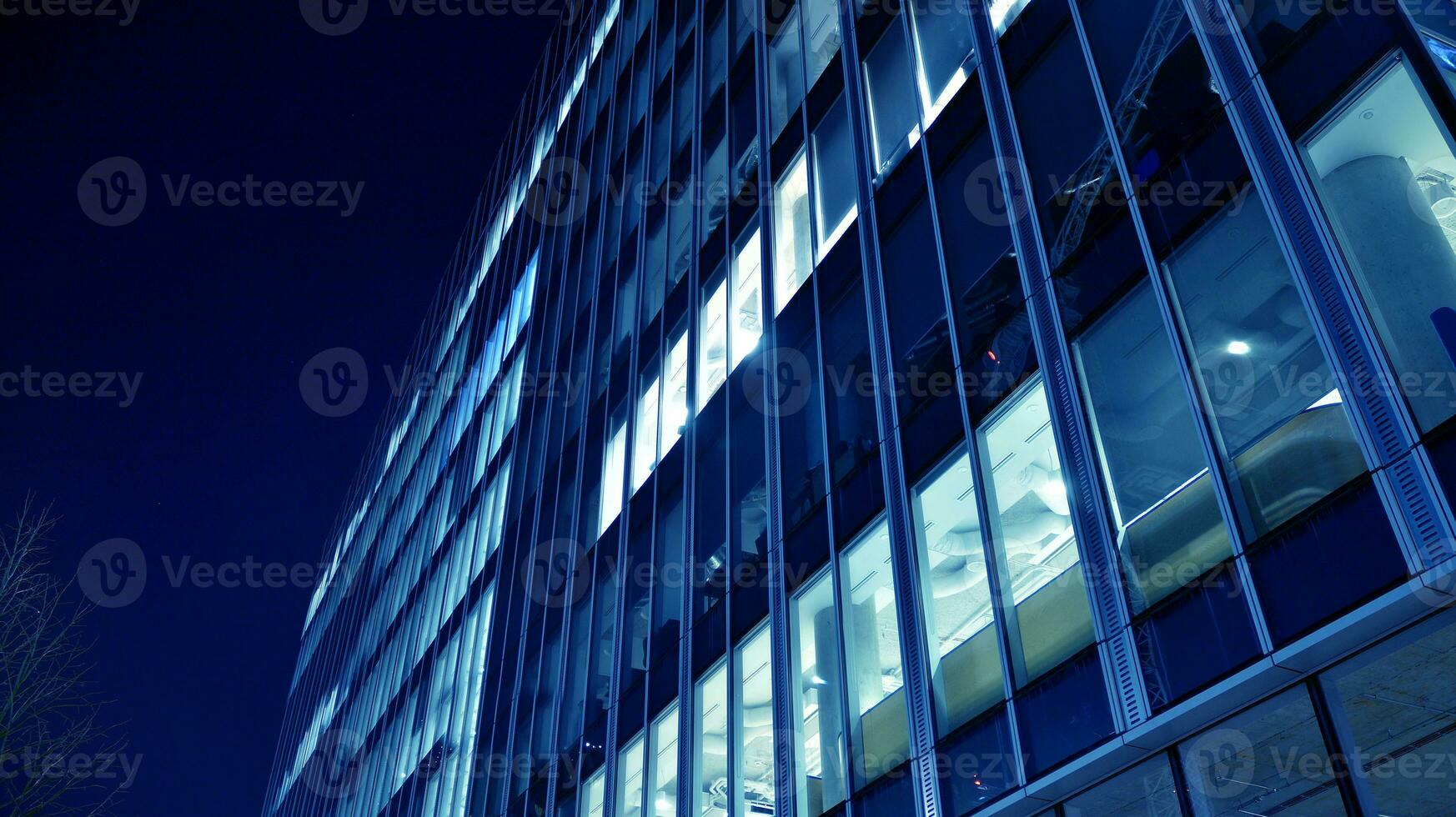 Pattern of office buildings windows illuminated at night. Glass architecture ,corporate building at night - business concept. Blue graphic filter. photo