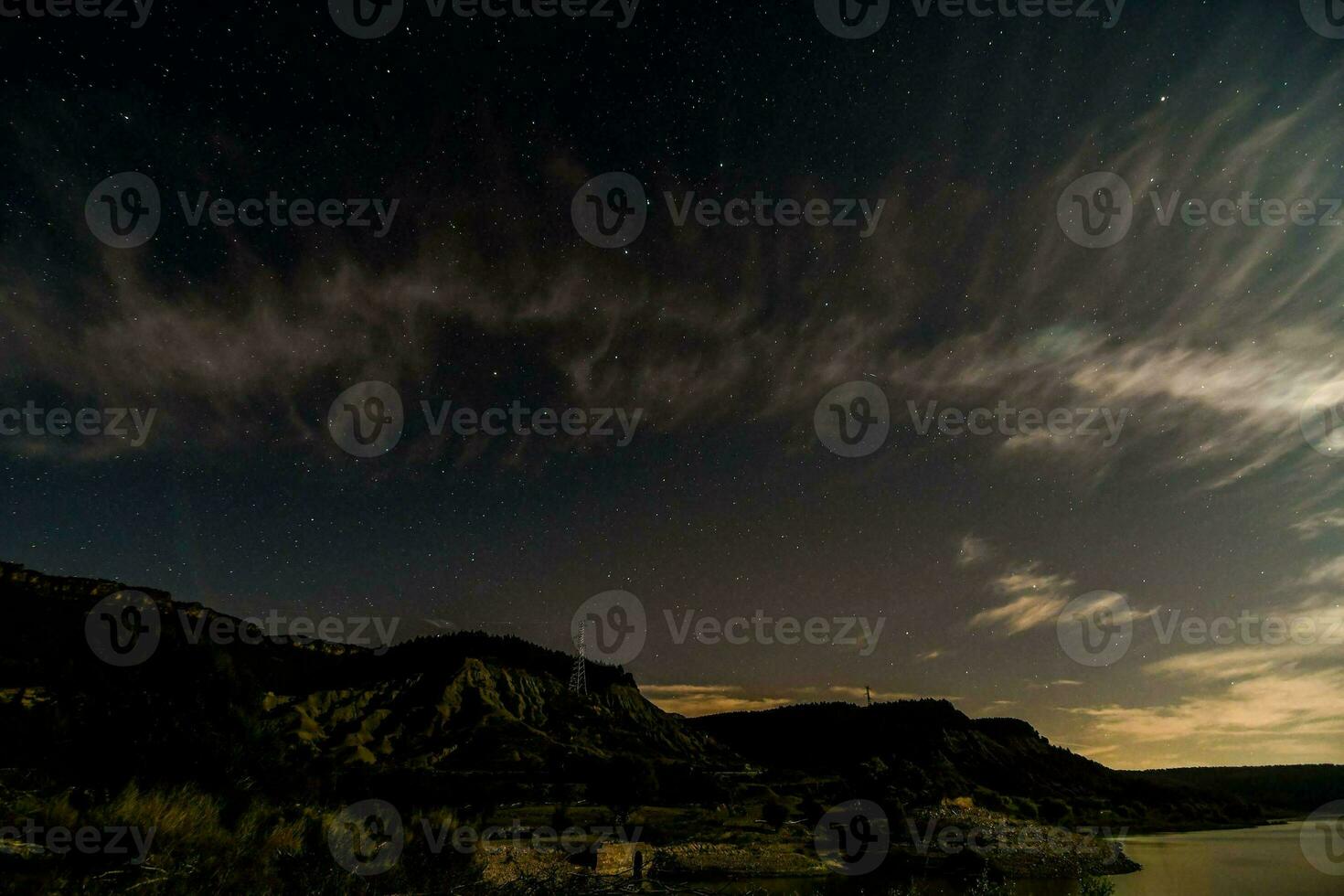 el noche cielo terminado un lago con nubes y estrellas foto