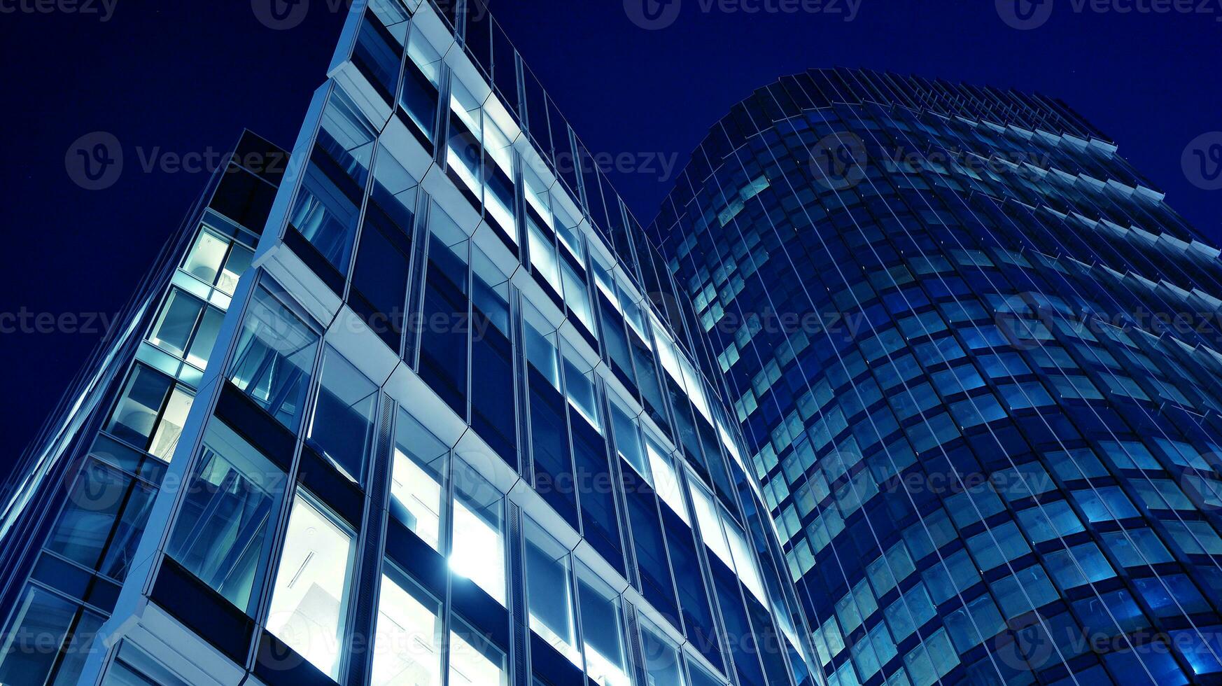 Pattern of office buildings windows illuminated at night. Glass architecture ,corporate building at night - business concept. Blue graphic filter. photo