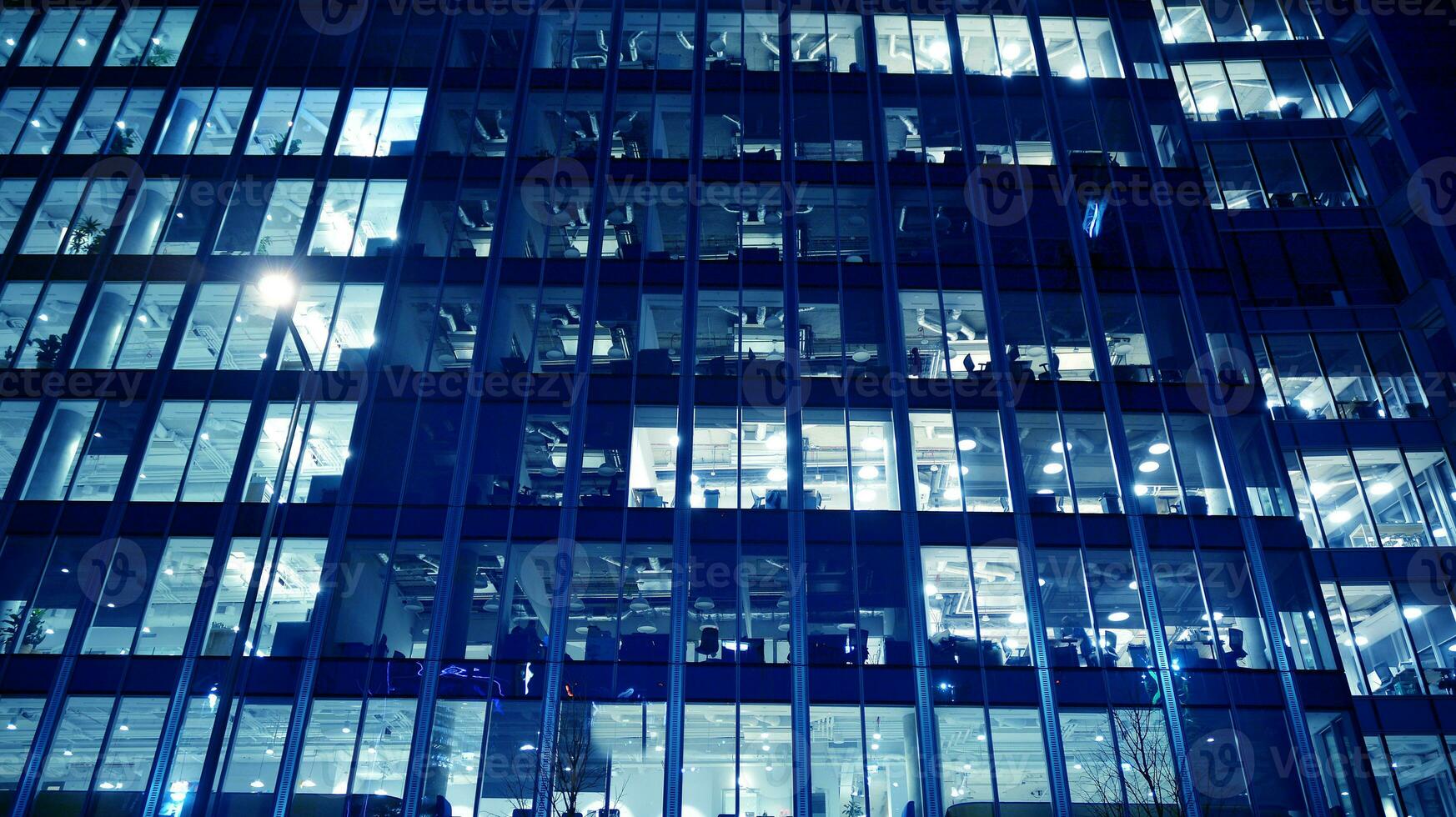 Pattern of office buildings windows illuminated at night. Glass architecture ,corporate building at night - business concept. Blue graphic filter. photo