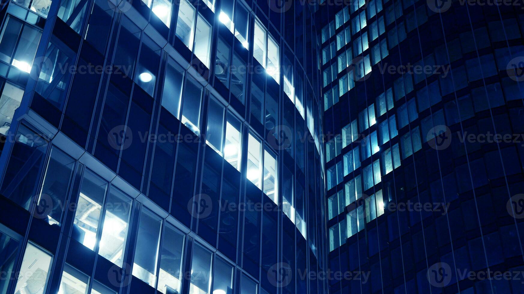 Pattern of office buildings windows illuminated at night. Glass architecture ,corporate building at night - business concept. Blue graphic filter. photo
