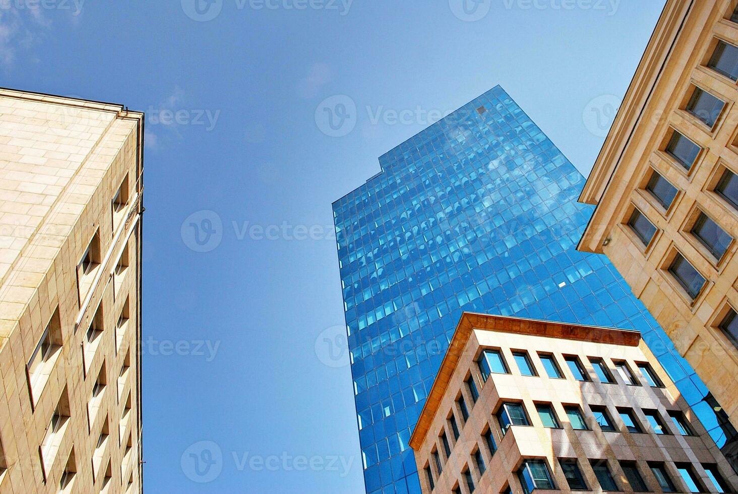 Structural glass wall reflecting blue sky. Abstract modern architecture fragment photo