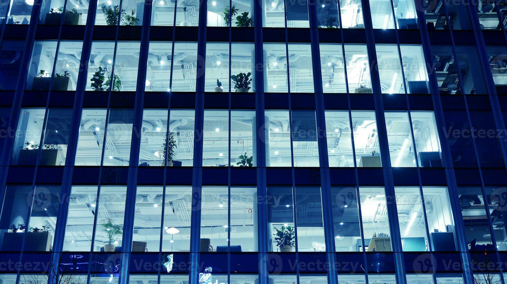 Pattern of office buildings windows illuminated at night. Glass architecture ,corporate building at night - business concept. Blue graphic filter. photo