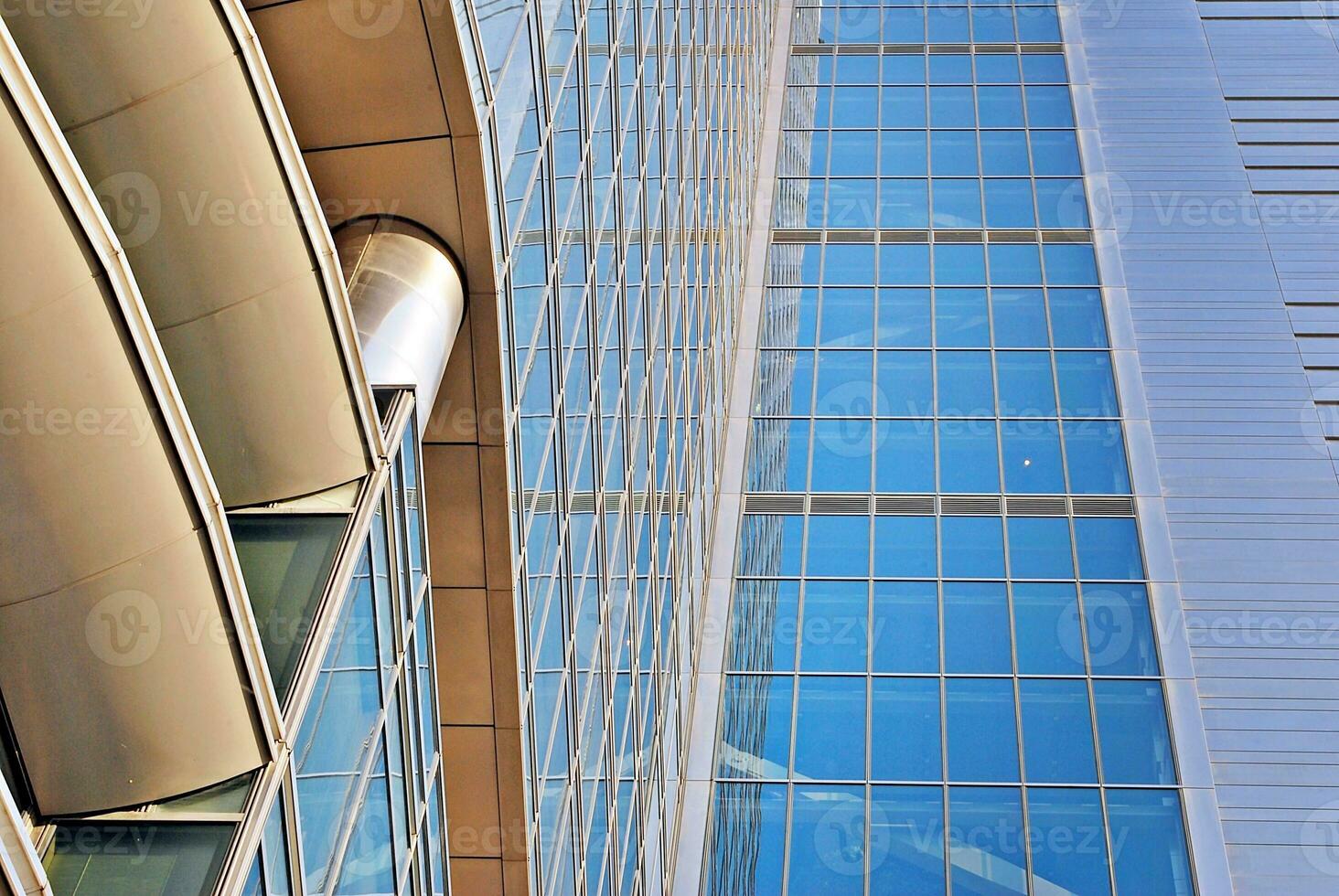 Structural glass wall reflecting blue sky. Abstract modern architecture fragment. photo