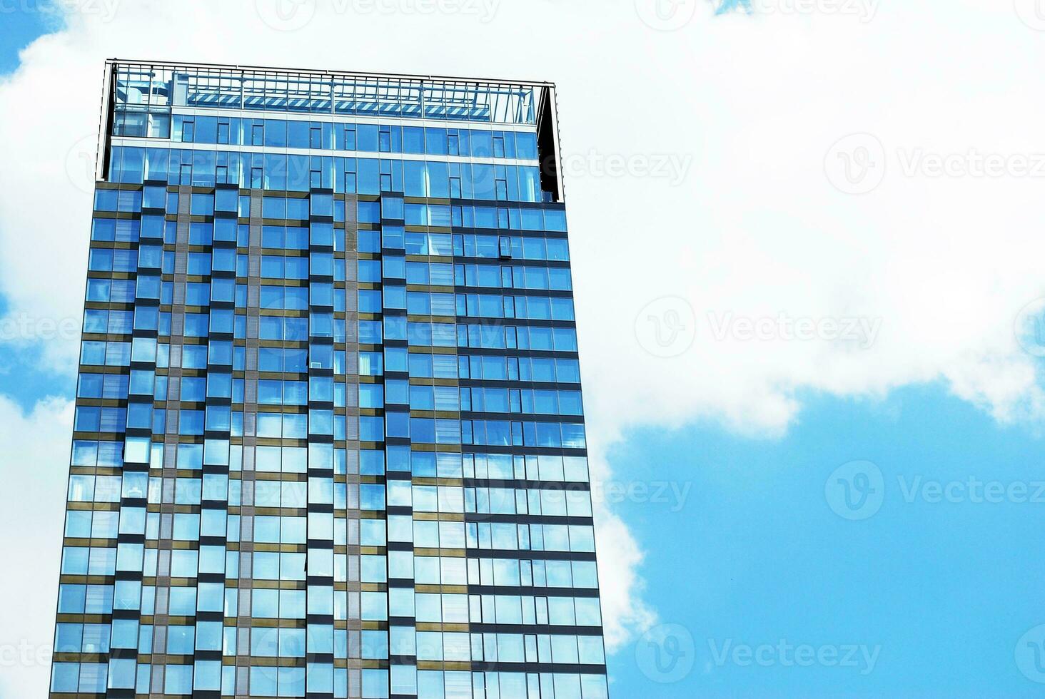 Structural glass wall reflecting blue sky. Abstract modern architecture fragment. photo