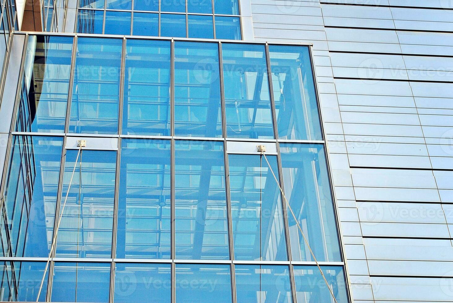 Structural glass wall reflecting blue sky. Abstract modern architecture fragment. photo