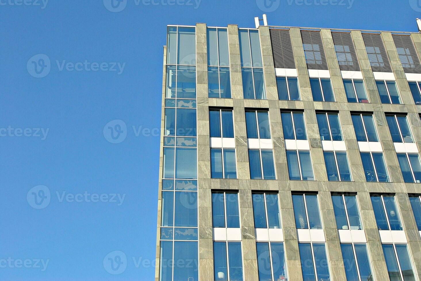 Structural glass wall reflecting blue sky. Abstract modern architecture fragment. photo