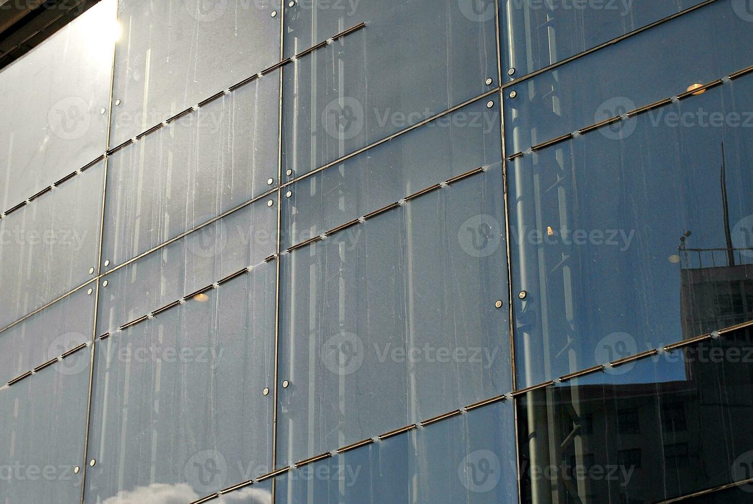 Structural glass wall reflecting blue sky. Abstract modern architecture fragment. photo