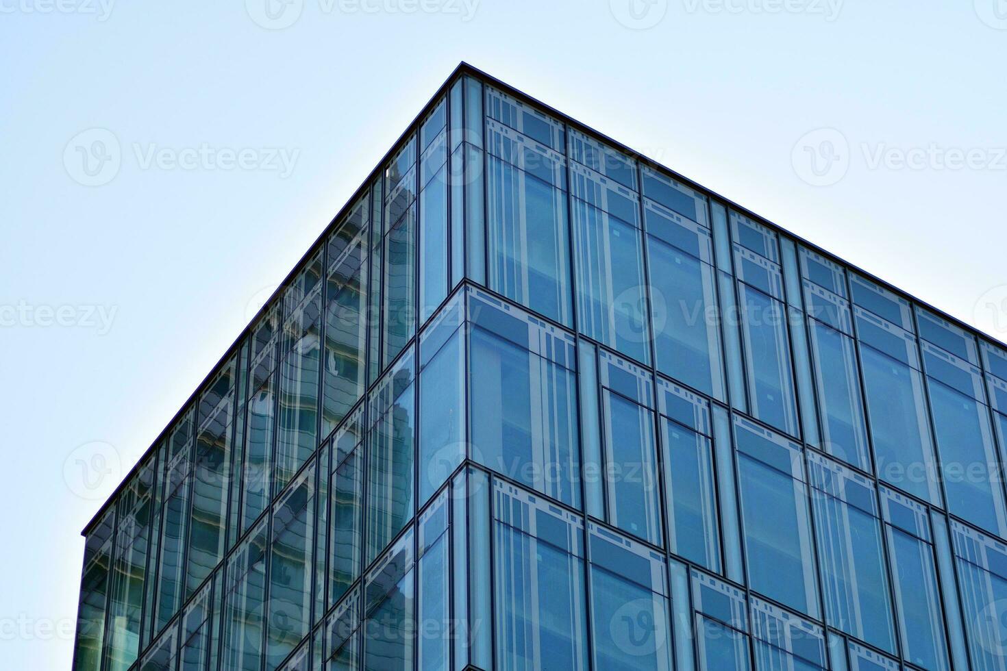 Structural glass wall reflecting blue sky. Abstract modern architecture fragment. photo