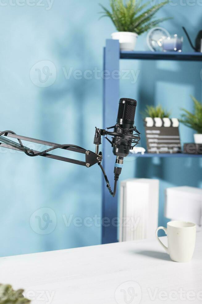 Professional microphone for podcast sound recording at empty blogger workspace. Black mic equipment for digital content creating in modern vlogger home studio with no people photo