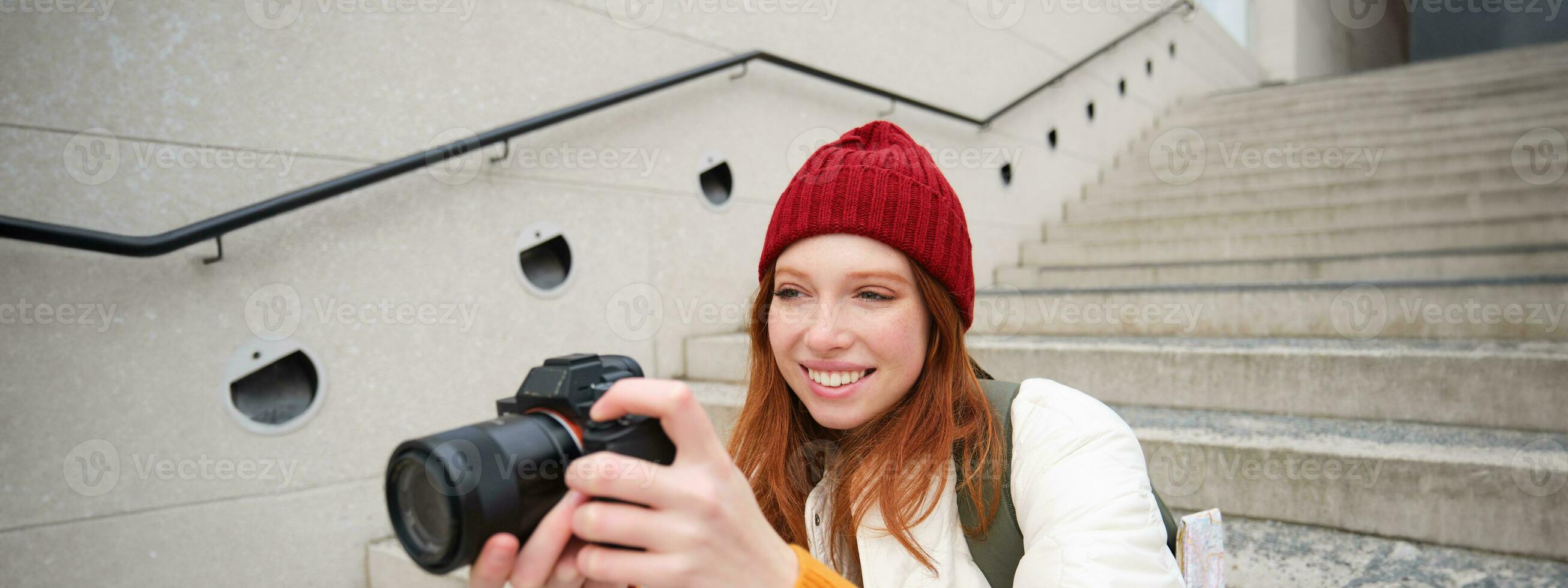 urbano personas y estilo de vida. contento pelirrojo mujer toma fotos, participación profesional digital cámara, fotografiando en calles foto