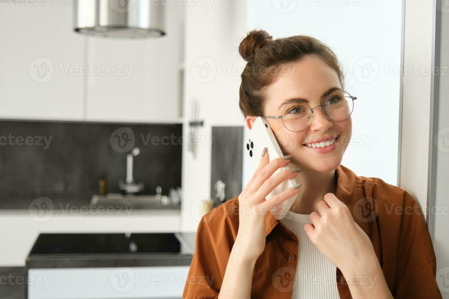 Portrait of happy smiling young woman at home, talking on mobile phone, calling friend and having nice conversation, answer telephone photo