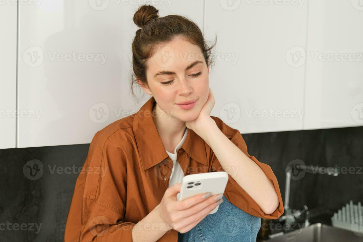 Portrait of beautiful young woman with smartphone, using mobile app, reading message or news feed on telephone photo