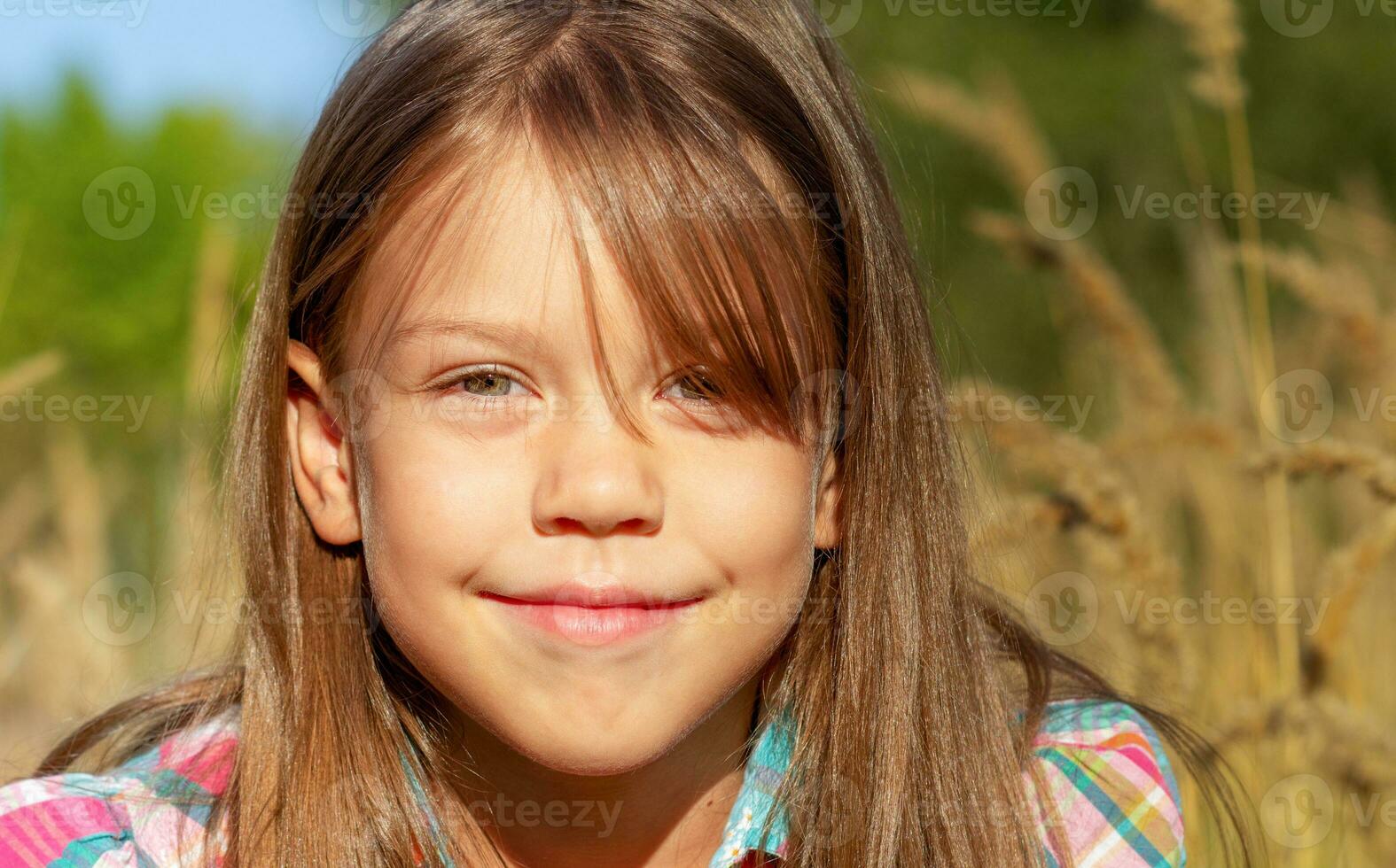 retrato de caucásico pequeño niña de 6 6 7 7 años sonriente y mirando a cámara fuera de en otoño campo foto